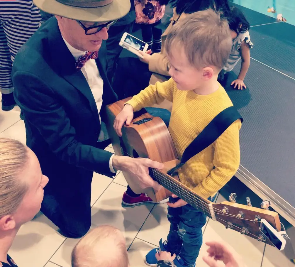 Et barn prøver en guitar sammen med en musiker