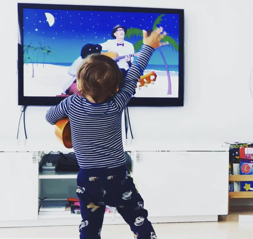 Et barn rører ved en musikvideo på en skærm